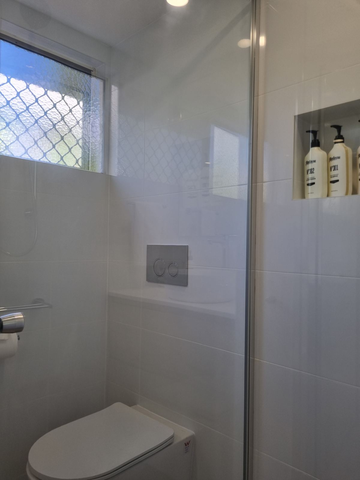 Bathroom with frameless shower screen, wall-hung toilet and frosted window