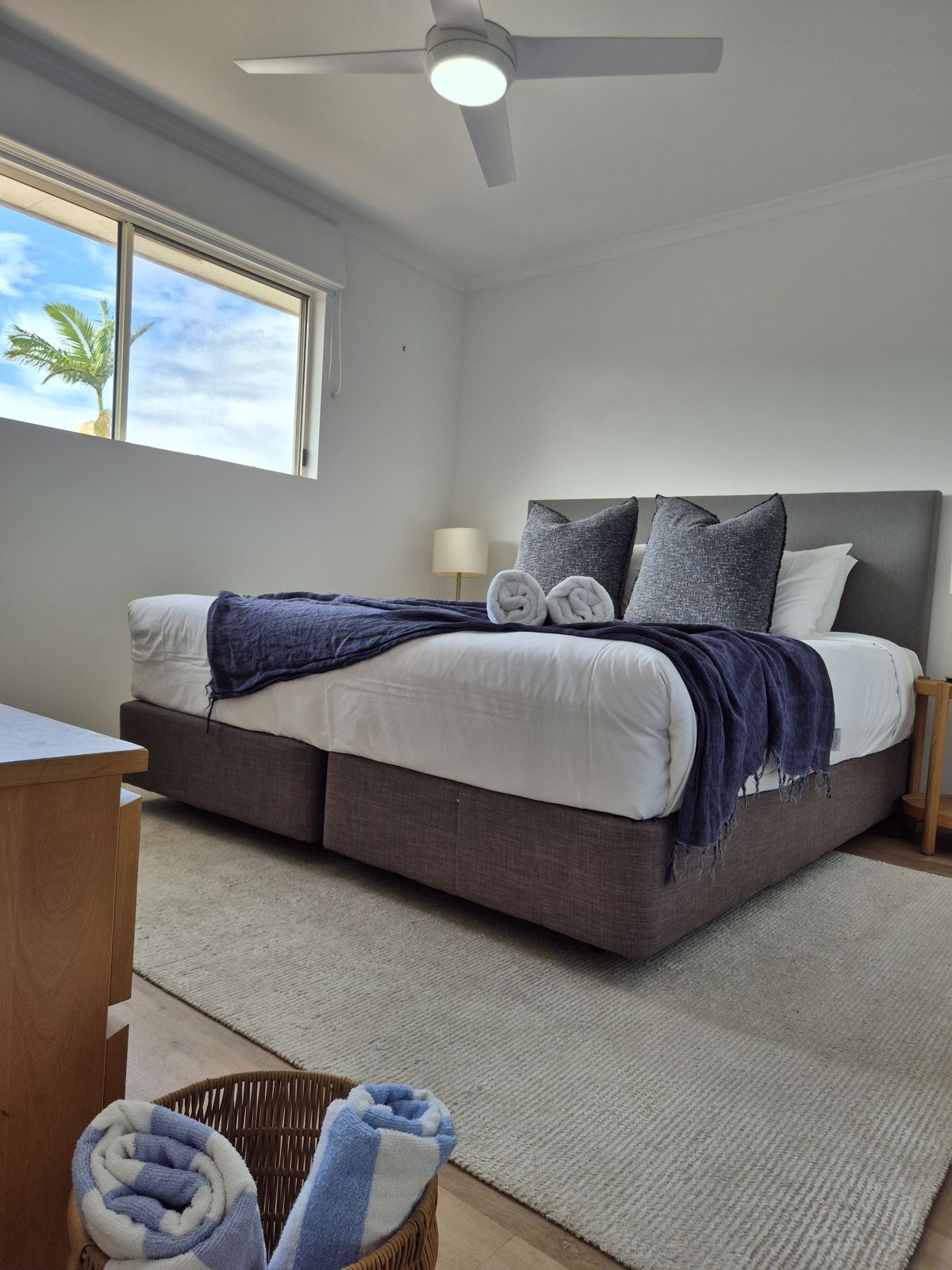 King bed with fresh white linen, a navy throw and striped beach towels
